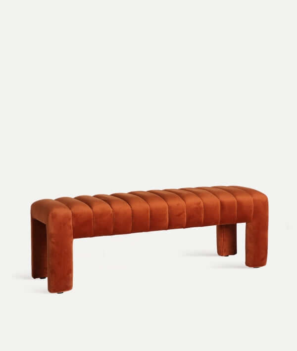 El pie de cama HALLE presenta un tapizado de terciopelo ámbar, un moderno diseño rectangular (127×43×43 cm), cuatro patas y un asiento acolchado y estriado, perfecto para añadir estilo a tu dormitorio.