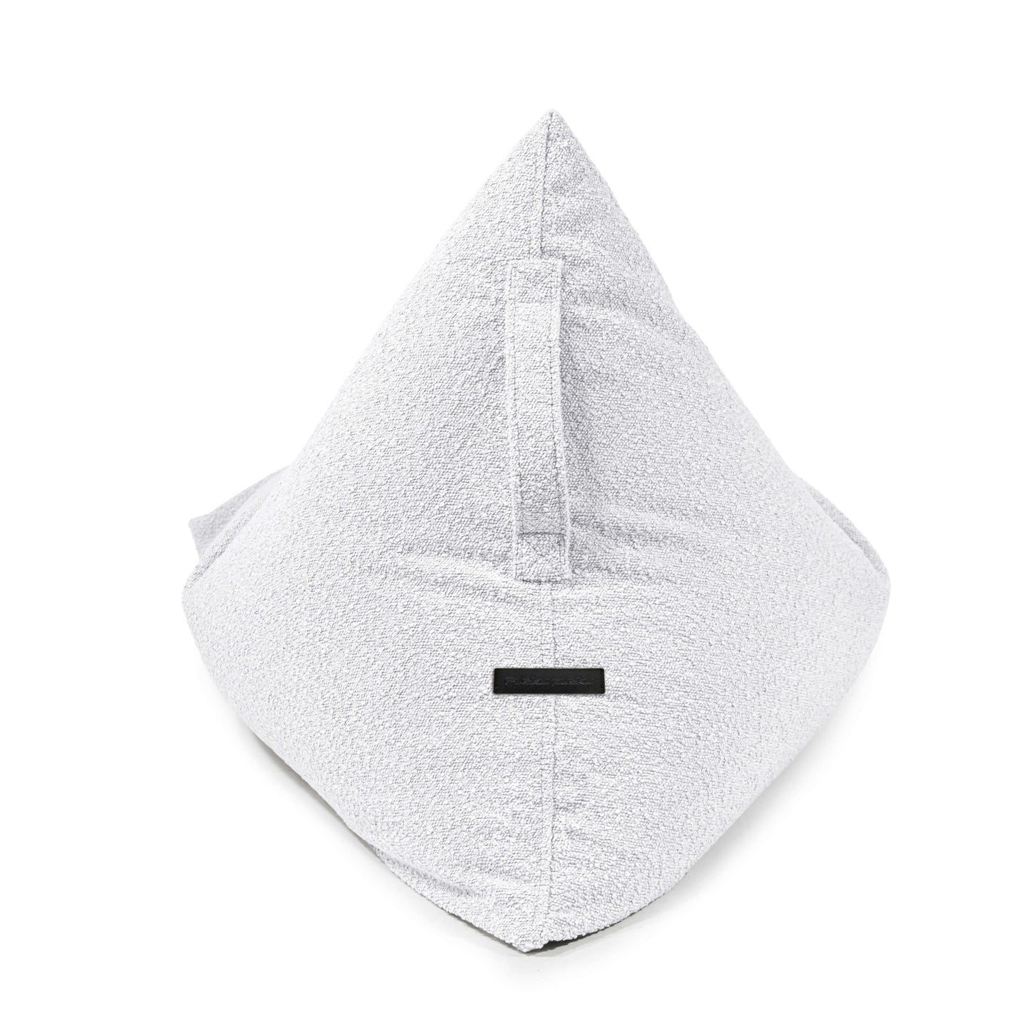 El puff infantil Bean bag RAZZY MADU, de suave tejido bouclé ignífugo (75×110×65 cm), es un asiento blanco en forma de pirámide con asa y etiqueta negra, perfecto como moderno mobiliario infantil para cualquier espacio.