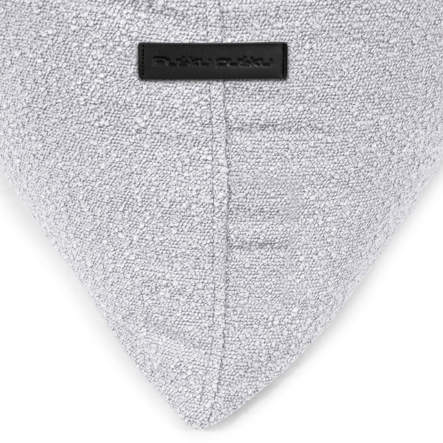 Primer plano de un puff puff infantil RAZZY MADU de tela bouclé gris claro (75×110×65 cm) con una etiqueta negra cerca de la costura superior, perfecto para habitaciones infantiles modernas y seguro con material ignífugo.