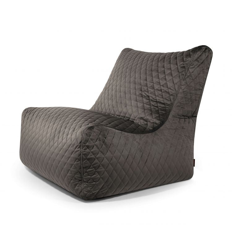 El Bean bag Seat 100 Lure Luxe es un sillón acolchado sin brazos de color gris oscuro con un aspecto suave y acolchado y un asiento bajo, que proporciona un cómodo asiento que recuerda a un bean bag, mostrado sobre un fondo blanco.