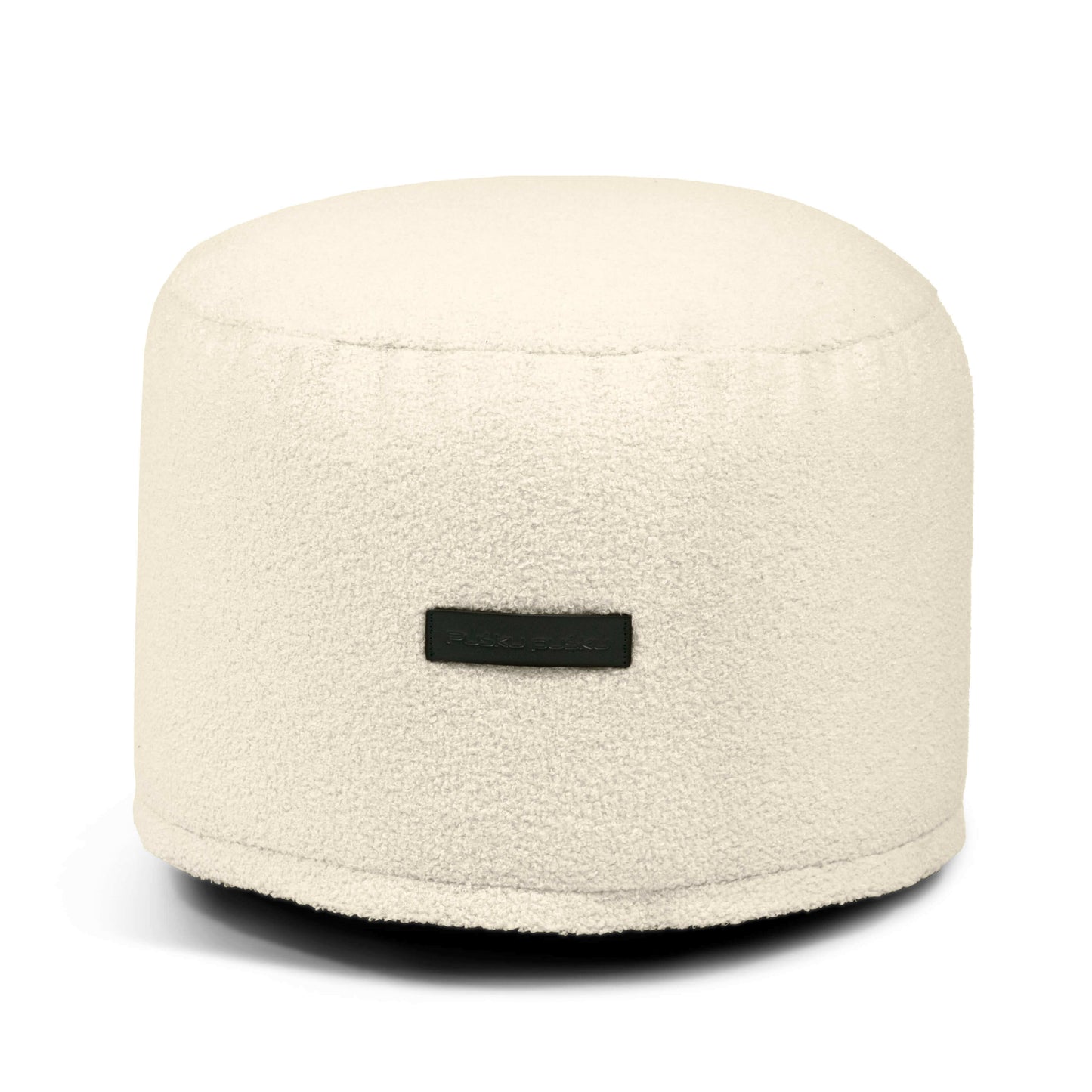 Un Puff de borreguito MINI TEDDY compacto y redondo (40×40×30 cm) para el dormitorio o el salón, con una superficie de textura suave y una pequeña etiqueta rectangular negra en la parte delantera.