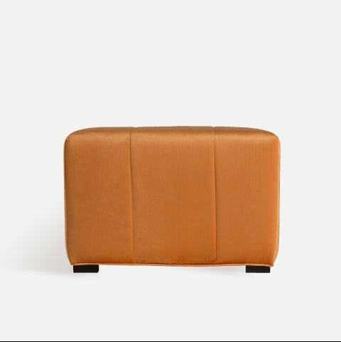 El puf cuadrado en terciopelo Geloux, un puf rectangular de color naranja con costuras a la vista, se destaca elegantemente sobre un fondo gris claro. Ideal para la decoración de interiores, su tono vibrante realza cualquier espacio con sofisticación.