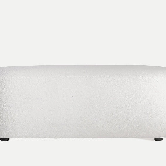 El Puff tapizado en algodón bouclé Winsum, con su diseño rectangular blanco y superficie texturizada, añade un toque elegante al fondo liso como una sofisticada pieza de decoración del hogar.