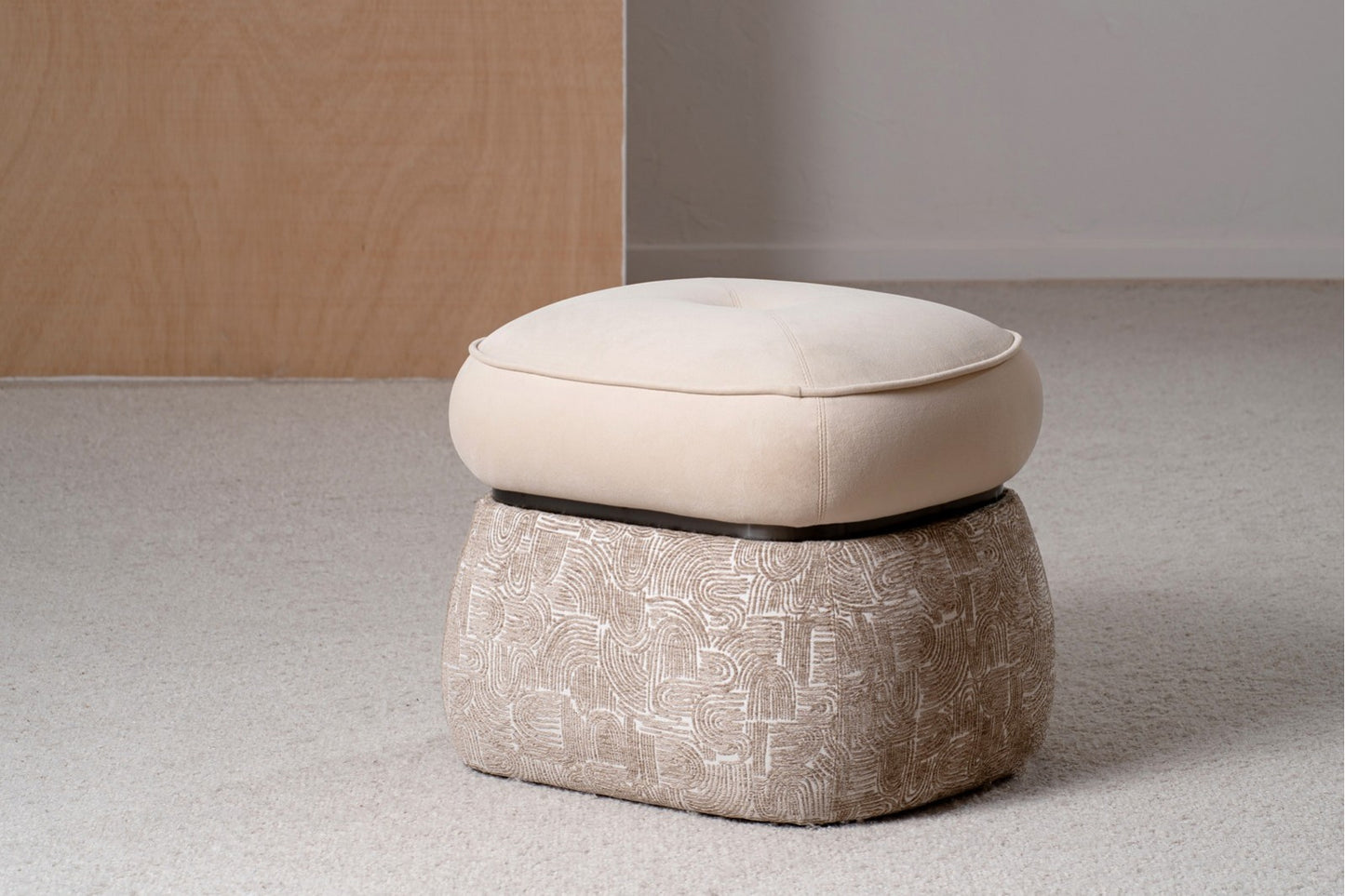 Un conjunto de dos otomanas cuadradas DUNA contemporáneas (51×45×43 cm) tapizadas en beige y camel con una base de aro de metal negro mate se asienta sobre una alfombra clara cerca de una pared de madera.