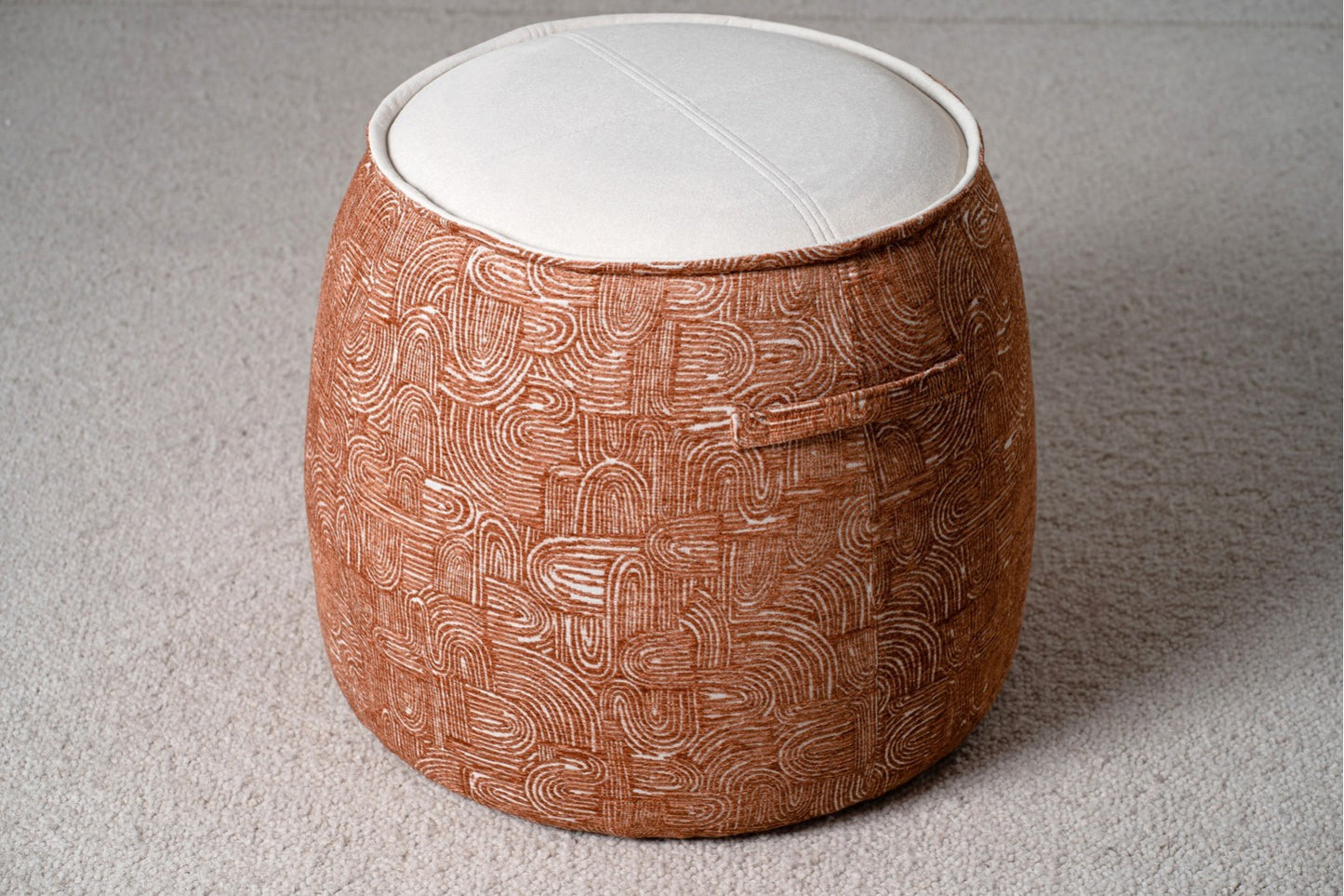 Un set de 2 pufs redondos EREA contemporáneos (50×50×40 cm), tapizados en teja y marfil, con asas laterales y vivo doble, sobre alfombra beige clara.