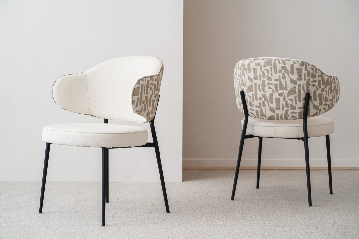 Set de 2 sillas de comedor CLOE tapizadas en beige y piedra, patas de metal negro, diseño contemporáneo, sobre alfombra clara y junto a una pared blanca.