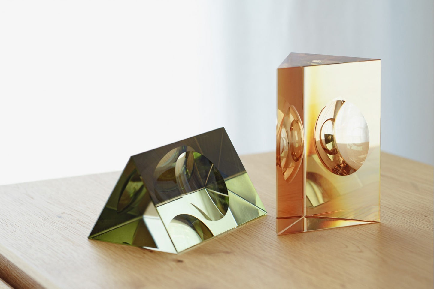 Set de 2 piezas decorativas de cristal en colores verde y champagne, diseño geométrico TRIÁNGULO, con formas originales y cortes circulares, destaca elegantemente sobre una superficie de madera.