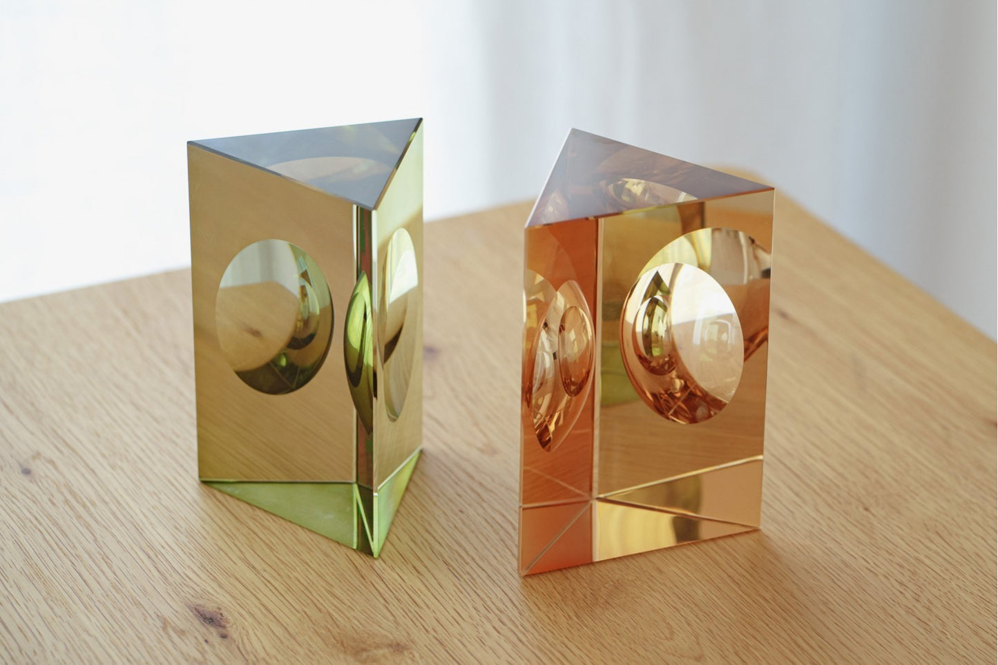 Este set de 2 piezas decorativas de cristal en colores verde y champagne, diseño geométrico TRIÁNGULO, presenta esculturas con cortes circulares, ideales para realzar cualquier espacio con un toque moderno y elegante.