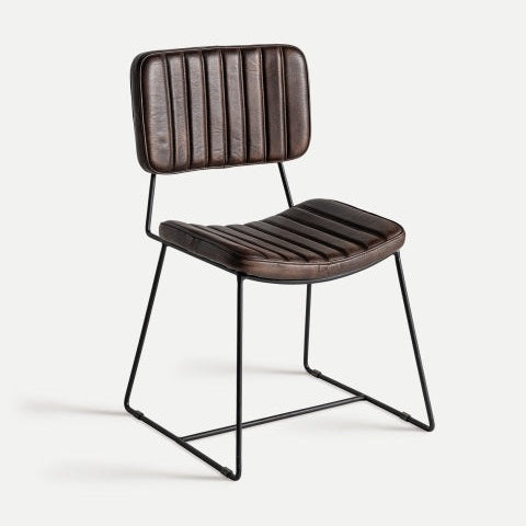 La silla de comedor en piel y metal Issert presenta un diseño de cuero marrón con costuras verticales en el asiento y el respaldo, sostenido por un elegante marco de metal negro con patas de trineo, que incorpora una estética moderna e industrial.