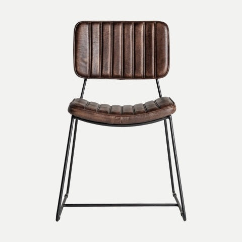 La silla de comedor Issert, de piel y metal, presenta un asiento de piel marrón con respaldo acanalado, sostenido por una elegante estructura de metal negro, que le confiere un diseño moderno e industrial. Ideal para añadir estilo a cualquier comedor.