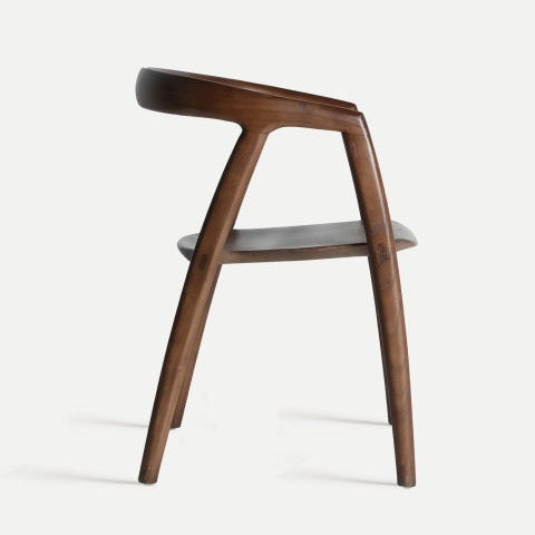 Vista lateral de la elegante Silla de comedor con reposabrazos en madera de olmo Labrit, una moderna silla de madera con respaldo curvo y patas en ángulo, que ofrece comodidad y estilo.