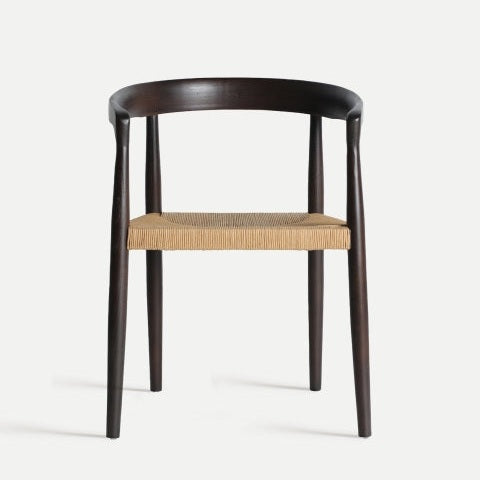 La silla de comedor en madera de olmo Leynie irradia elegancia y funcionalidad con su respaldo curvo oscuro, soportes verticales hechos de resistente madera de olmo y un asiento de tejido ligero que realza tanto el estilo como la comodidad.