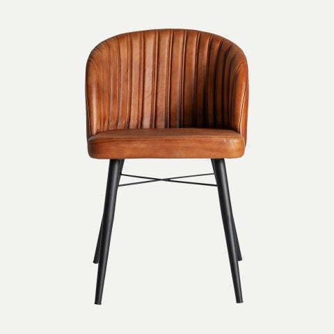 La silla de comedor en piel y metal Luard, una silla de cuero marrón con respaldo redondeado y acanalado y patas de metal negro, encarna el diseño moderno y proporciona estilo y funcionalidad sobre un fondo blanco liso.