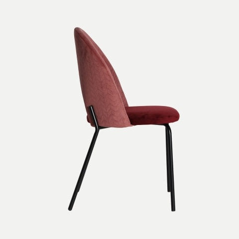 Vista lateral de la Silla de comedor en terciopelo y hierro Sarkad, que muestra un asiento y respaldo acolchados en rojo terciopelo burdeos con elegantes patas de metal negro, sobre un fondo blanco liso.