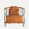 El sillón Chaize de estilo industrial presenta cuero marrón, un marco de metal cromado y un respaldo acanalado sobre un fondo gris claro.