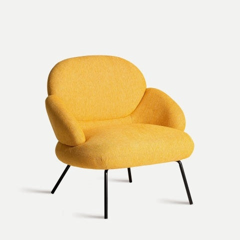 Presentamos el Sillón en Chenilla Mostaza Dokkum, un sillón amarillo vibrante con respaldo y asiento redondeados. Sus patas angulares de metal negro aportan un toque de sofisticación moderna, sobre un fondo blanco impecable.