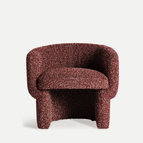 El Sillón tapizado jaspeado Leke, un sillón de tela roja con textura, presenta un respaldo redondeado y un cojín de asiento grueso con elegancia y comodidad sobre un fondo liso y claro.