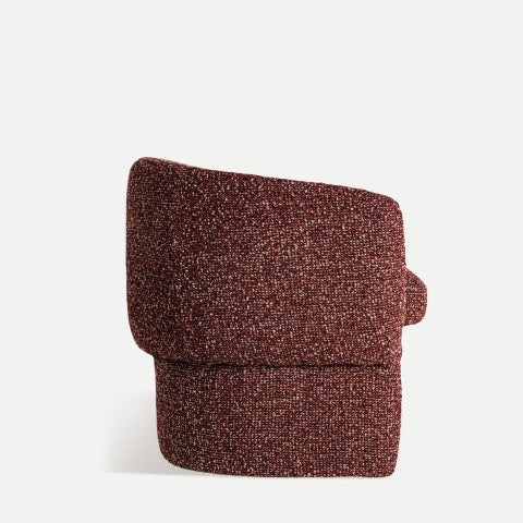 El Sillón tapizado jaspeado Leke es una silla roja, texturizada y angular con un diseño moderno que encarna la esencia de la estética moderna, destacando audazmente sobre un fondo blanco liso.