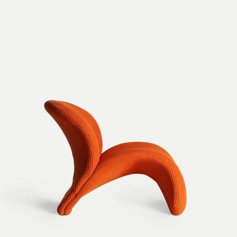El sillón moderno tapizado naranja Vianne N presenta una forma escultural y abstracta en tela naranja vibrante y un diseño ergonómico, resaltado sobre un fondo blanco liso.