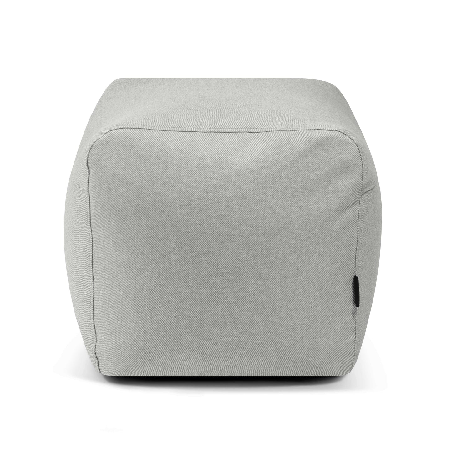 El Pouf Plus 50 Riviera - uso exteriores es un puf en forma de cubo de tela de color gris claro con una superficie lisa y una pequeña etiqueta negra en el lateral, perfecto como asiento extra, mostrado sobre un fondo blanco.