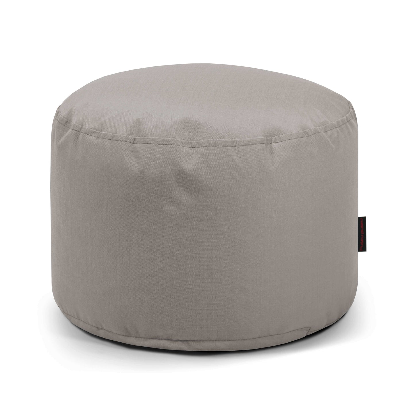El Pouf Mini Colorin - uso exteriores es una otomana redonda de color gris claro fabricada con tejido certificado OEKO-TEX, con costuras sencillas, una pequeña etiqueta lateral negra y un asiento compacto y versátil ideal para cualquier espacio.