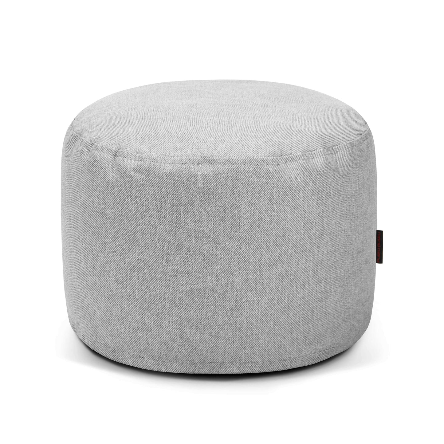 El Pouf Mini Riviera - uso exterior es un puf redondo de color gris claro con una superficie lisa y una pequeña etiqueta de tela lateral, que ofrece un asiento versátil, mostrado sobre un fondo blanco liso.