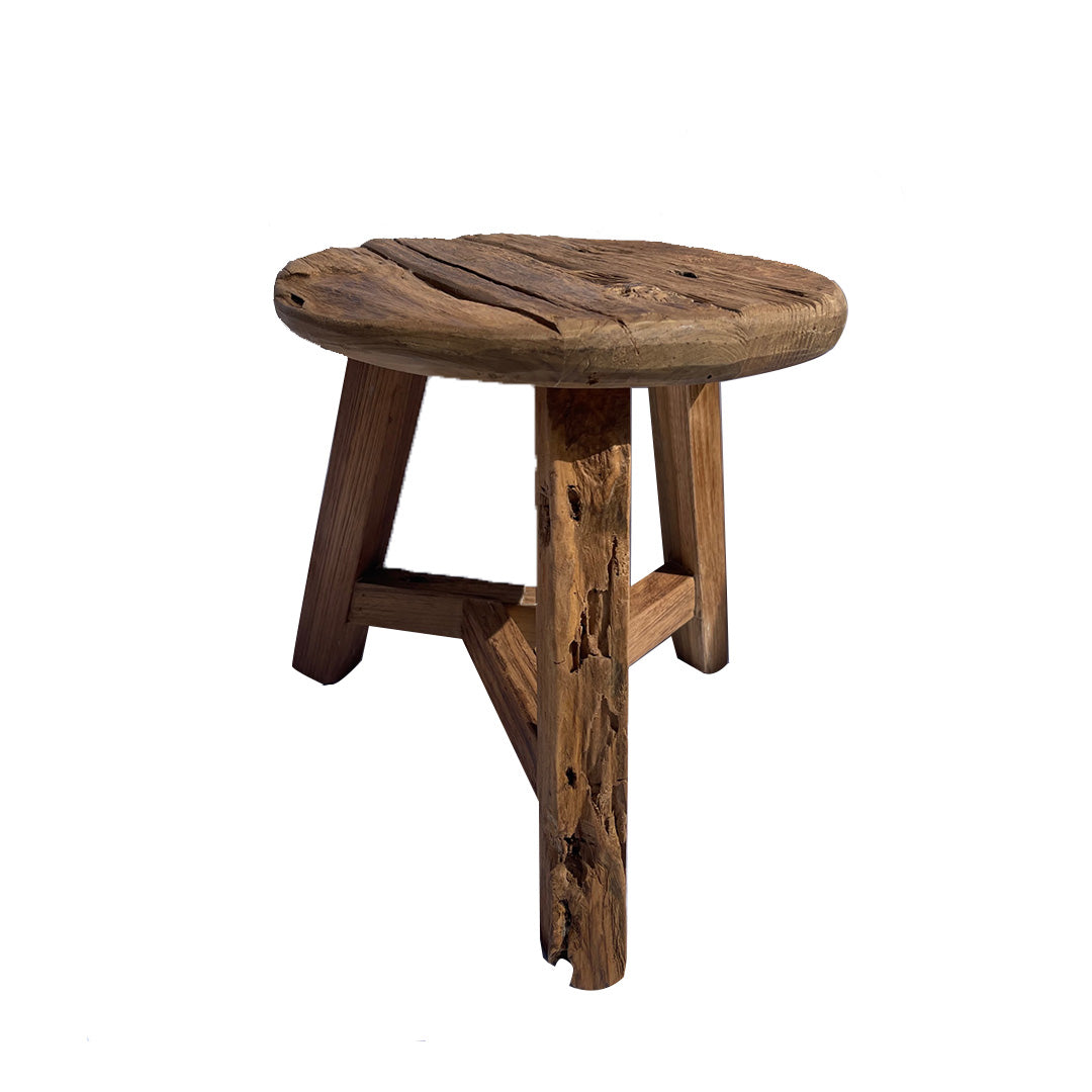 La Banqueta Rústica en Madera Natural Rustic S es un taburete pequeño, redondo, de tres patas y estilo rústico, elaborado en madera natural, expuesto sobre un fondo blanco.
