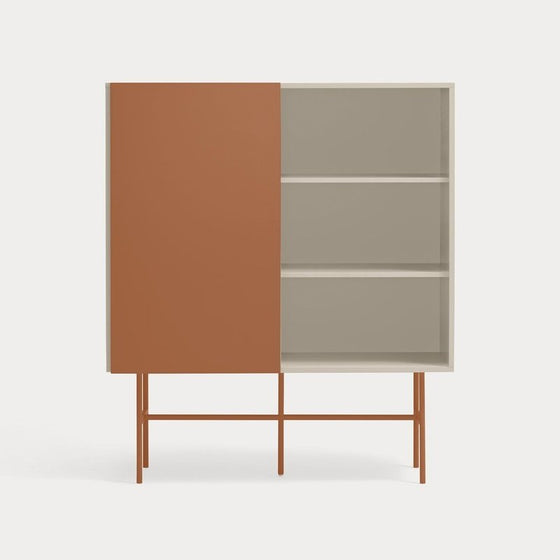 Un Mueble Auxiliar Nube 1P4C con una puerta corredera de color óxido y tres estantes expuestos, elevados sobre un delgado marco de metal sobre un fondo liso, ejemplifica el diseño minimalista.