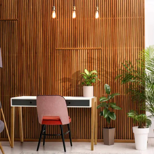 Un Escritorio Concept en un espacio con diseño nórdico que incluye una silla roja y plantas en macetas, todo ello frente a una pared de listones de madera.